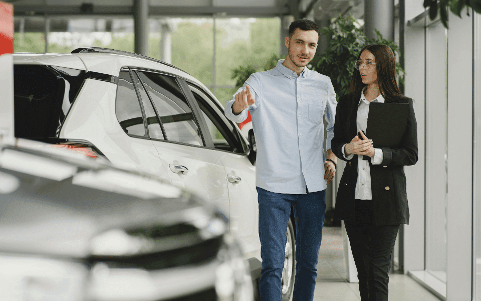 Dealership employee showing a car to a customer